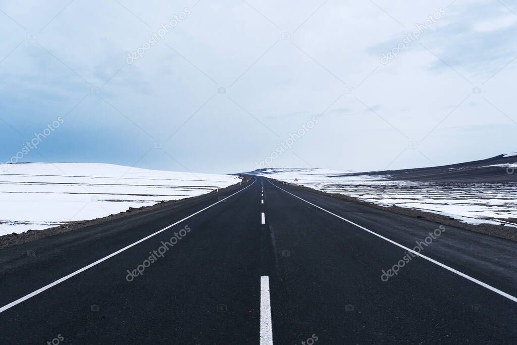 View of an emtpy asphalt road with lanes and snow in winter.