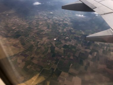 Bir uçak penceresinden tarlaların ve tarlaların havadan görünüşü.