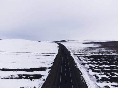 Kışın tek şeritli ve karlı bir yol manzarası.