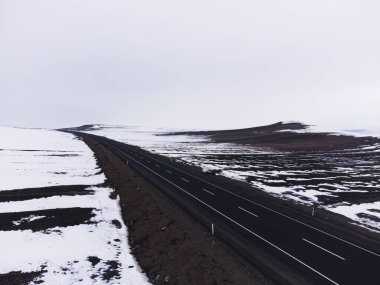 Kışın tek şeritli ve karlı bir yolun hava çapraz görüntüsü..