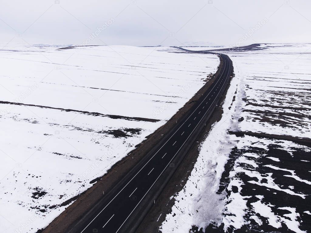 Aerial diagonal view of a road with one lane and snow in winter.