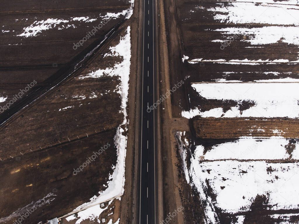 Aerial view of a road with one lane and snow in winter.
