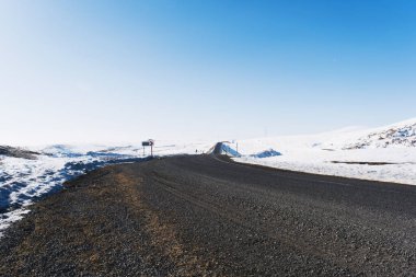 Kış mevsiminde şeritleri ve karlı bir asfalt yol manzarası.