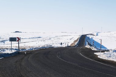 Kış mevsiminde şeritleri ve karlı bir asfalt yol manzarası.