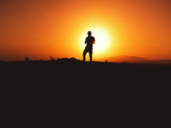 Silhouette Eines Mannes Mit Fedora Hut Bei Sonnenuntergang Auf Einem — Stockfoto