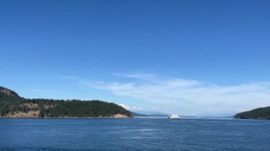 The iconic blue and white Washington ferry passes the San Juan Islands on a sunny and perfectly calm day in summer. San Juan Islands - Washington