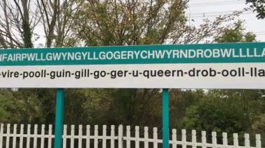 A railway station platform sign in the village with the longest place name in the UK, Llanfairpwllgwyngyll on the island of Anglesey in Wales.