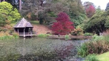 The skating pond at Bodnant Gardens with trees and the boat house in the background, taken in Autumn with beautiful foliage - Conwy, Wales, UK.