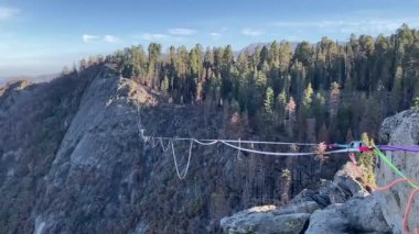 İnsan, Sequoia Ulusal Parkı 'ndaki bir kanyonun üzerinde ip boyunca yürürken dengede durur. Güneşli bir günde, baharın sonlarında Kaliforniya 'da Three Rivers yakınlarında mavi bir gökyüzüyle çekildi.