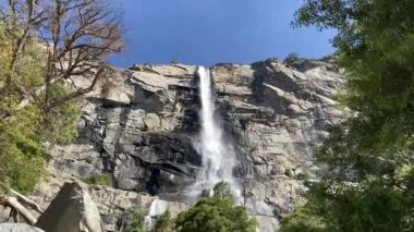 Tueulala Şelalesi, Hetch Hetchy Vadisi 'ndeki destansı granit kayalıkların üzerinde tam bahar zamanı akıyor. Baharda mavi bir gökyüzünde çekildi - Yosemite Ulusal Parkı, Kaliforniya, ABD