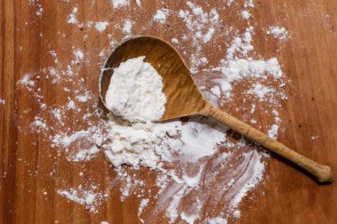 Kırmızı-kahverengi ahşap masada beyaz buğday ezmeli eski tahta kaşık.