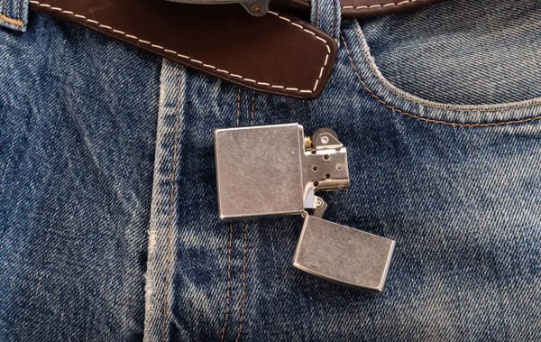 Metal lighter on denim jeans with leather belt — Stockfoto