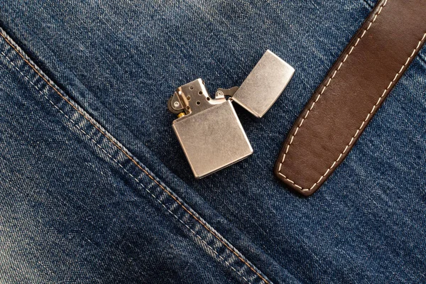 Vintage metal lighter and leather belt on denim — Zdjęcie stockowe