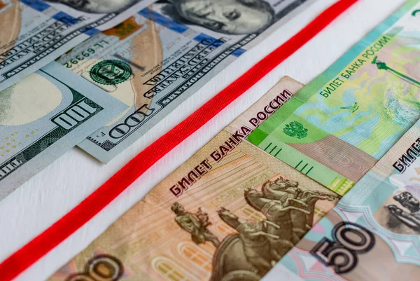 Red ribbon separating banknotes of US dollars and Russian rubles — Stock Photo, Image