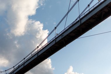 Mavi gökyüzünün arkaplanındaki bulutlu yaya köprüsünün silueti