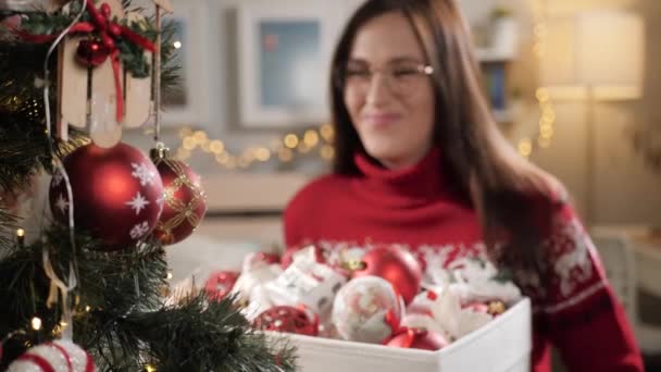 Nő karácsonyi játékokkal. Boldog vonzó nő kezében doboz karácsonyi játékok a kezében, és mosolyogva. Lassú mozgás. — Stock videók