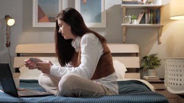 Kadın telefon eder ve kahve içer. Kadın yatak odasında oturuyor ve akıllı telefon ekranına mesaj yazıyor ve fincandan kahve ya da çay içiyor. Yavaş çekim görünümü