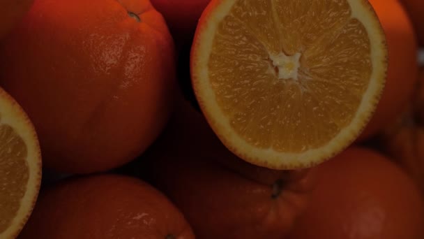 Апельсин. Вертикальный вид луча света освещает срезанные оранжевые фрукты в тени. Крупный план — стоковое видео