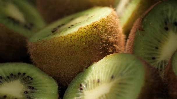 Des kiwis. La caméra se déplace lentement et montre des kiwis coupants dans l'ombre avec un faisceau de lumière du soleil brillant. Macro shot — Video