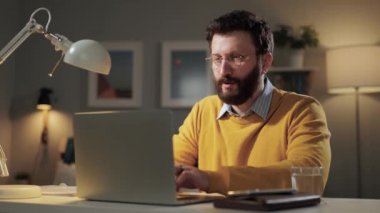 Mutlu adam, başarı duygusu. Heyecanlı, mutlu, sakallı, gözlüklü, bilgisayarına bakan adam dizüstü bilgisayar ekranında duygusal tepkiler veriyor.