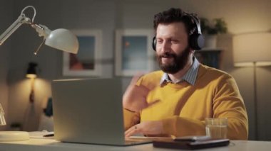 Çevrimiçi öğrenme, uzaktan eğitim, video çağrısı, e-öğrenme, uzaktan sunum konsepti. Merkez ofisteki bilgisayardaki web kamerasına bakan olumlu adam kablosuz kulaklığı çıkarıp hoşça kal diyor.