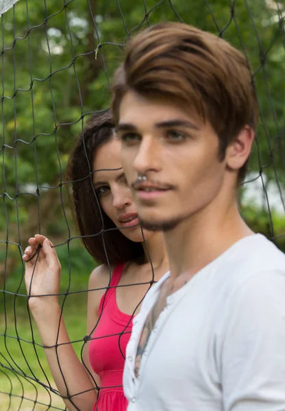 Woman holding hands over the net and looks at the man — Stock Photo, Image