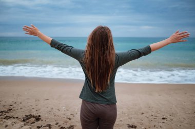 Kadın fırtınadan önce sonbahar kumsalında deniz havasının tadını çıkarıyor. Seyahat yaşam tarzı konsepti. Dans eden ve eğlenen hoş bir kadının açık hava portresi.