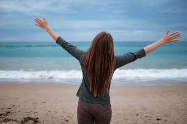 Kadın fırtınadan önce sonbahar kumsalında deniz havasının tadını çıkarıyor. Seyahat yaşam tarzı konsepti. Dans eden ve eğlenen hoş bir kadının açık hava portresi.