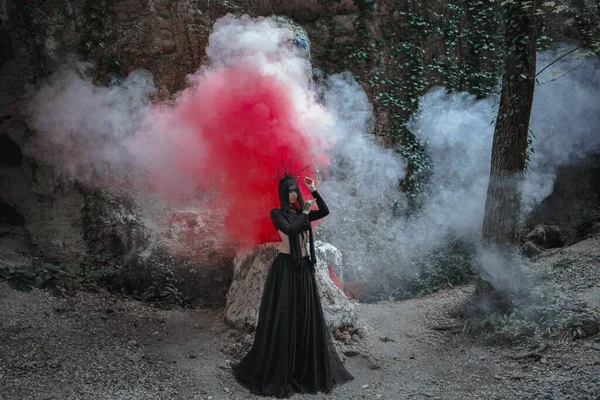 魔女の若い女性は黒のドレスに立って 暗い霧の森の中で彼女の頭の上に冠 ハロウィンコスチュームのためのダークパーティー — ストック写真