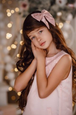 Mutlu Noeller ve mutlu tatiller. Sevimli küçük kız? Pembe elbise Noel ağacının oradaki şenliğin tadını çıkarıyor.