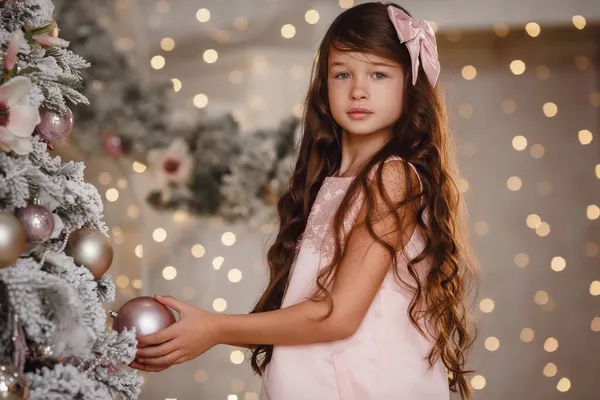 メリークリスマスとハッピーホリデー 可愛い子ちゃん クリスマスツリーでお祝い気分を楽しむピンクのドレス — ストック写真