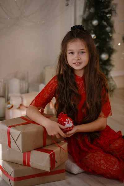 メリークリスマスとハッピーホリデー 陽気かわいいです可愛いです子供女の子で赤ドレスとともに現在 — ストック写真