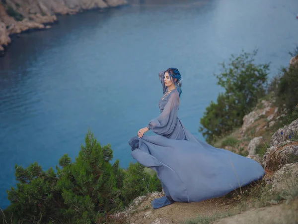 海の山を見て灰色のドレスで青い髪の若い美しい女性 自然の中で女性 ファッション写真 絹織物風になびく — ストック写真