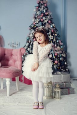 Mutlu Noeller ve mutlu tatiller. İçeride Noel ağacının yanında güzel elbiseli şirin bir kız bebek..