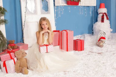 Noel ağacının altında gülümseyen, süslemeli bir kız çocuğu. Yeni yıl. Kış tatili.