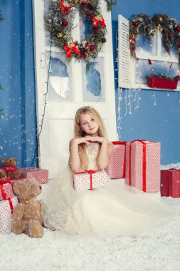 Mutlu Noeller ve mutlu tatiller. İçeride Noel ağacının yanında güzel elbiseli şirin bir kız bebek..