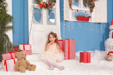 Noel ağacının altında gülümseyen, süslemeli bir kız çocuğu. Yeni yıl. Kış tatili.