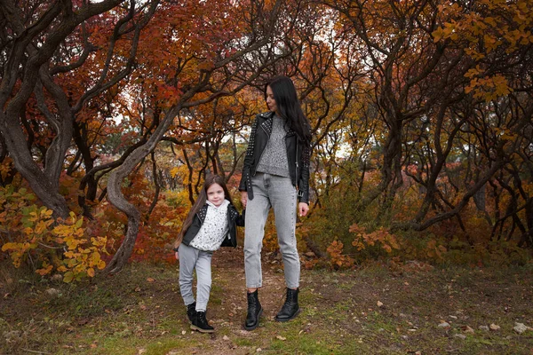 幸せな家族の母親と子供の娘が秋の散歩で遊んで笑っています 母親と子供の関係 ファッショナブルな母と娘でスタイリッシュな外観で同じ革のジャケットとセーター — ストック写真