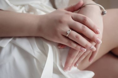 Gelinin güzel bir portresi. Makyajlı saç stili. Beyaz elbiseli muhteşem bir kadın. Eller yakın plan.