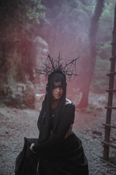 Mujer Joven Bruja Está Pie Vestido Negro Corona Cabeza Bosque —  Fotos de Stock