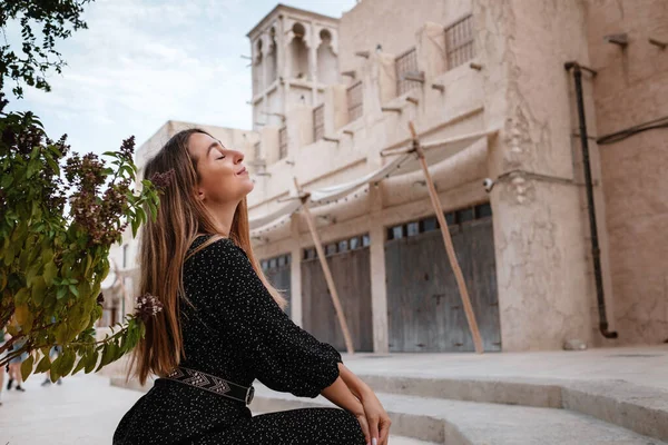 砂漠の真ん中にある古いアラブの町や村の通りを歩く黒いドレスを着て幸せな女性旅行者 セーフ ドバイの観光と冒険の概念 — ストック写真