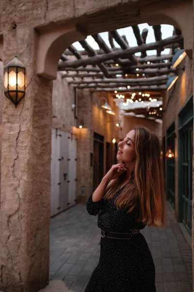 砂漠の真ん中にある古いアラブの町や村の通りを歩く黒いドレスを着て幸せな女性旅行者 Seef Dubai通りにある伝統的なアラビア式オイルランプ — ストック写真