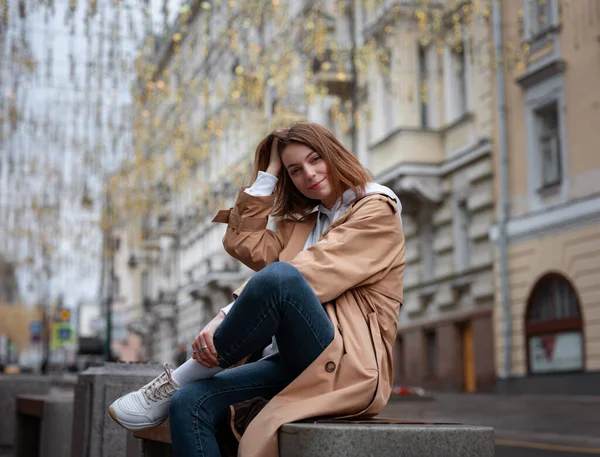 美しいベージュのコートで美しい女性は秋の曇りのモスクワで歩くと 街の中心部に装飾された居心地の良い通りに座っています ストリートスタイル ロシアの概念への旅行 — ストック写真