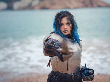 Medieval knight woman in armor prays, blessing before the battle. The Middle Ages history Fantasy photo. Beautiful female knight on the beach near mountains watching snow over sea