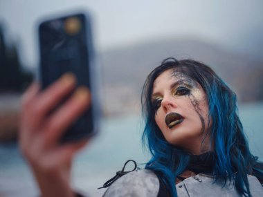 Ortaçağ şövalyesi kadın savaş öncesi dua ediyor. Orta Çağ tarihi fantezi fotoğrafı. Güzel bayan şövalye sahilde telefonda selfie çekiyor.