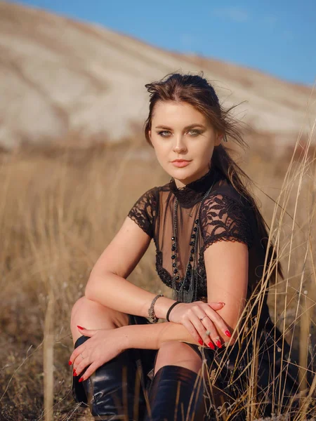 Fashionable woman on desert field near mountain wearing black dress. Wild west. Summer holidays dance.