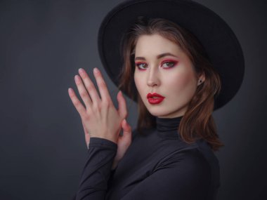 Siyah balıkçı yaka yaka ve koyu gri şapkalı kırmızı dudaklı çekici Asyalı kadın. Güzellik ve sağlık kavramı.