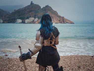 Ortaçağ şövalyesi kadın savaş öncesi dua ediyor. Orta Çağ tarihi fantezi fotoğrafı. Güzel bayan şövalye sahilde, dağların yakınında denizin üzerindeki karı seyrediyor.