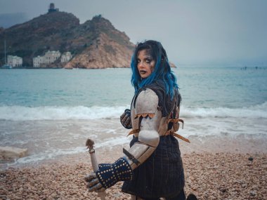 Ortaçağ şövalyesi kadın savaş öncesi dua ediyor. Orta Çağ tarihi fantezi fotoğrafı. Güzel bayan şövalye sahilde, dağların yakınında denizin üzerindeki karı seyrediyor.