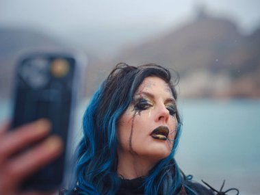 Ortaçağ şövalyesi kadın savaş öncesi dua ediyor. Orta Çağ tarihi fantezi fotoğrafı. Güzel bayan şövalye sahilde telefonda selfie çekiyor.